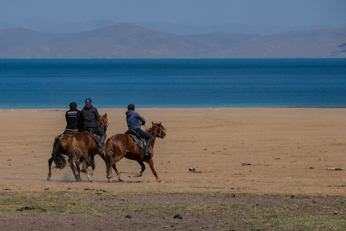 Habitants kirghizistan à cheval au lac son kul