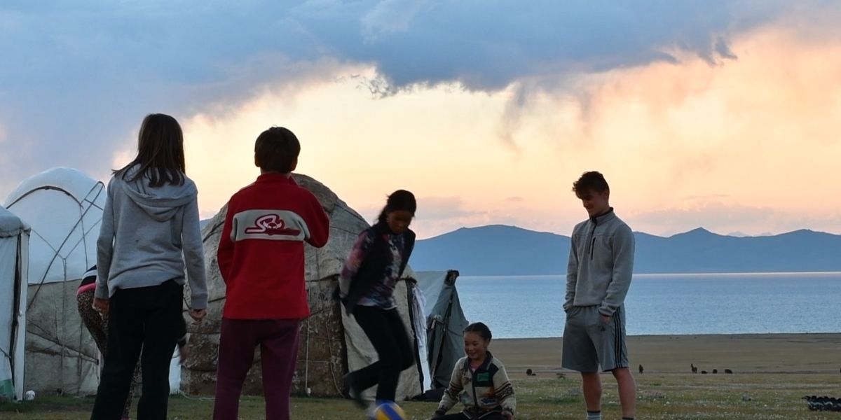 Enfants qui jouent au ballon devant les yourtes et le lac son kul au Kirghizistan